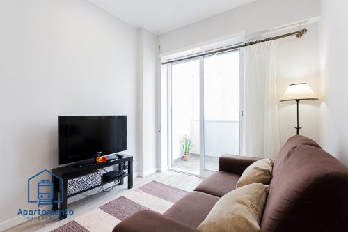 a living room with a couch and a large window at Apartamento da estação in Setúbal