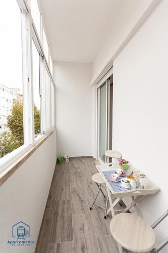 a white room with a table and chairs and windows at Apartamento da estação in Setúbal