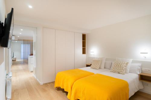 um quarto com uma cama grande e um cobertor amarelo em Fermin Suite - Iberorent Apartments em San Sebastián
