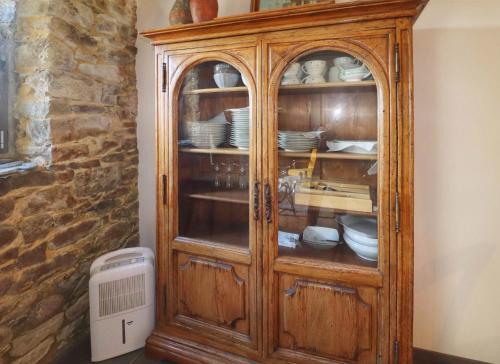 un meuble en bois avec de la vaisselle à côté d'un mur dans l'établissement Le petit gîte cosy de Kerigou avec vue mer et plage, à Saint-Pol-de-Léon