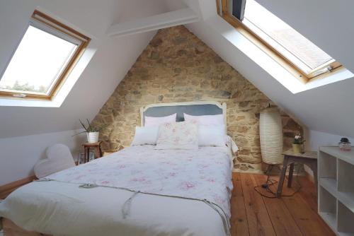 une chambre avec un grand lit dans un grenier dans l'établissement Le petit gîte cosy de Kerigou avec vue mer et plage, à Saint-Pol-de-Léon
