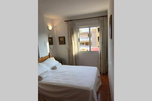 a bedroom with a white bed and a window at The Beach Apartment - Sea views in Cabo de Palos