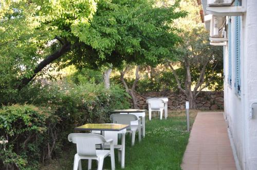 a row of tables and white chairs in the grass at Resort Fior di Sardegna in Posada