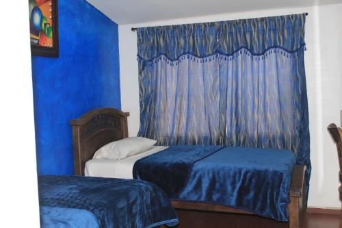 a bedroom with two beds and a blue curtain at Hotel Restaurante El Madroño Chia in Chía