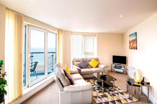 a living room with a couch and a large window at Just Stay Wales - Meridian Quay Apartments in Swansea