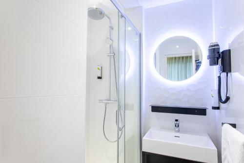 bagno con doccia, lavandino e specchio di L'Orée du Bois a Vittel