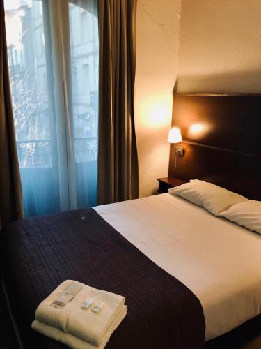 a hotel room with a bed and a window at Hôtel des Ambassadeurs in Toulouse