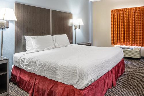 a hotel room with a large bed with white sheets at Suburban Studios Chattanooga Northeast - Ooltewah in Chattanooga