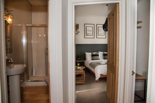 a bedroom with a bed and a bathroom with a sink at Finest Retreats - The Cotton Rooms in Matlock