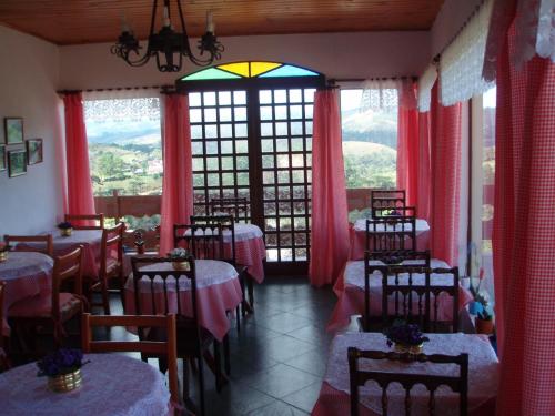 um restaurante com mesas e cadeiras numa sala com janelas em Pousada Cachyto de Cielo em Campos do Jordão