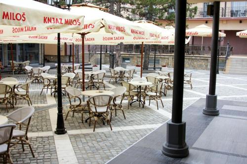 an outdoor cafe with tables and chairs and umbrellas at Hill Hotel Wellness & Spa in Jagodina