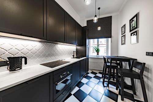 a kitchen with black cabinets and a table and chairs at Apartamenty Dominikańskie 2 in Toruń