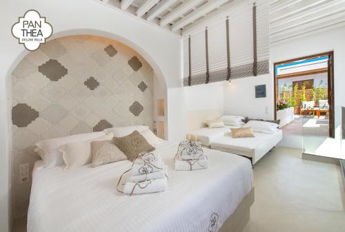 a white bedroom with two beds and a balcony at Villa Panthea in Líndos