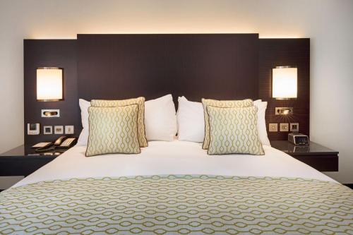 a bedroom with a large white bed with two lamps at Crowne Plaza Bahrain by IHG in Manama