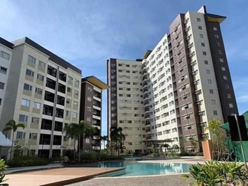 two tall buildings with a pool in front of them at AVIDA ATRIA T2-C short walk mall,esplanade,wifi,netflix,kitchen,pool in Iloilo City