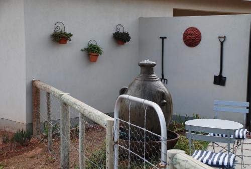 a white wall with potted plants and a vase at Gasteria Grange in Calitzdorp