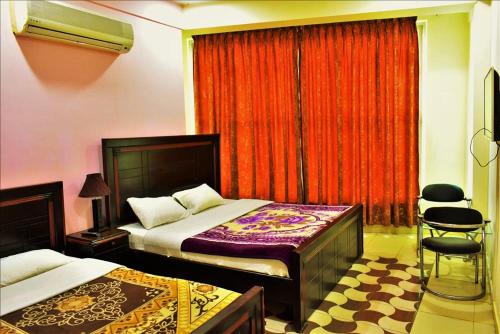 um quarto com 2 camas e uma janela com cortinas vermelhas em River Palace Hotel em Suat