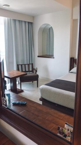 a bedroom with a bed and a table and a mirror at Hotel Fortin Plaza in Oaxaca City