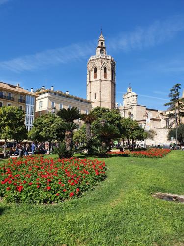 a building with a clock tower and a field of flowers at Mercat Suites in Valencia