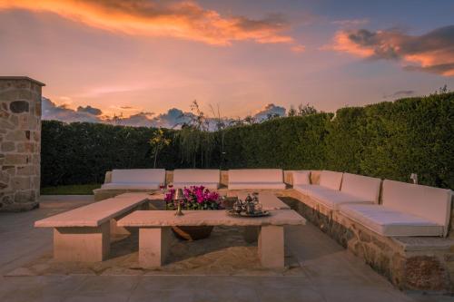 a patio with a bench and a table with flowers at Villa Shangri-La Zakinthos in Zakynthos Town