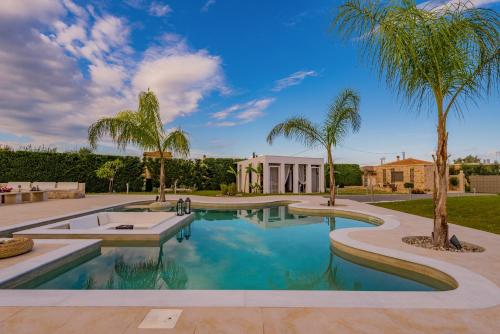 a swimming pool with palm trees and a building at Villa Shangri-La Zakinthos in Zakynthos Town