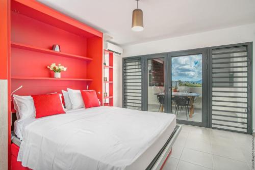 Un dormitorio rojo con una cama blanca y una mesa en STUDIO EQUIPE A L ETANG Z ABRICOTS, en Fort-de-France