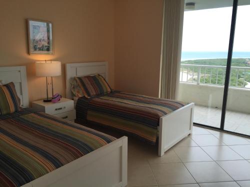 a bedroom with two beds and a view of the ocean at Beachfront 2 Bed 2 Bath Penthouse Condo in Marco Island
