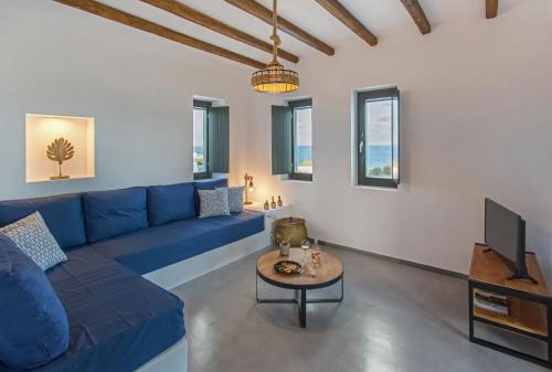 a living room with a blue couch and a table at Vastblue of Paros in Ambelas
