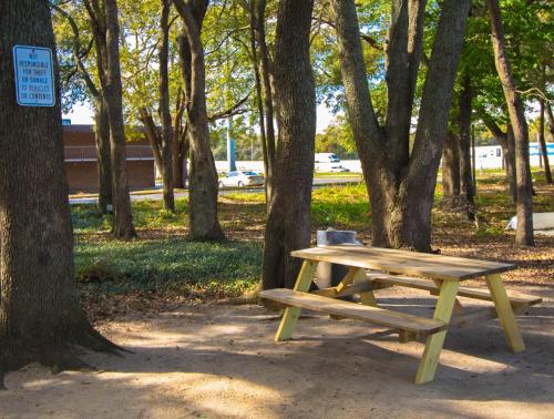 a picnic table and bench in a park with trees at Sweet Dream Inn - University Park in Pensacola