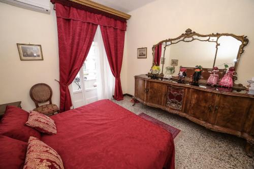 una camera con letto rosso e grande specchio di WELL COME - Lungomare SANTA LUCIA a Napoli