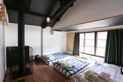 two beds in a room with a large window at Guesthouse Izame Ann in Nagaoka