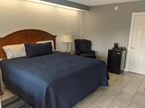 a bedroom with a blue bed and a chair at Budget Inn of Lodi in Lodi