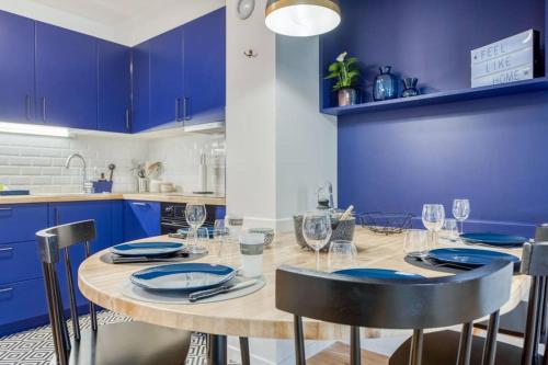 une cuisine avec une table en bois et des armoires bleues dans l'établissement La Serrisienne 3 - Val d'Europe Place Toscane - Disneyland Paris - 4 à 6 Personnes, à Serris