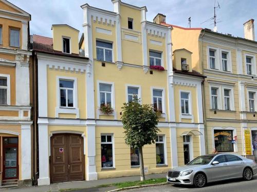 弗朗齊歇克礦泉村的住宿－Apartmány u Barči，停在黄色建筑前面的汽车