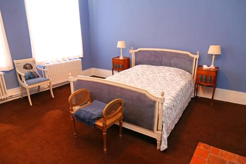 a bedroom with a bed and a chair and blue walls at Villa Theresa à 25 min de PAIRI DAIZA in Soignies