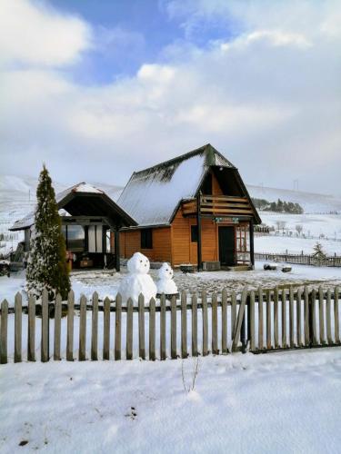 two snowmen sitting on a fence in front of a house at Brvnara Zlatiborka in Zlatibor