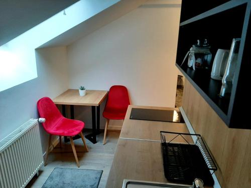 a small room with a table and two red chairs at Bulevard mansards in Satu Mare