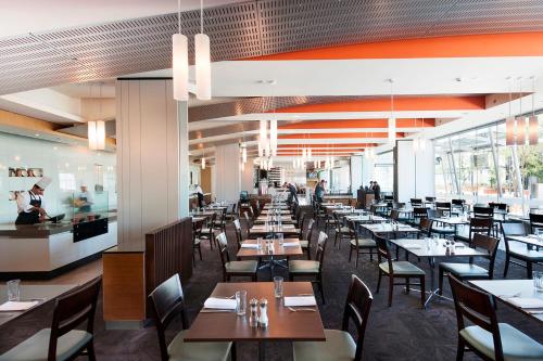 a restaurant with tables, chairs, and tables in it at Crown Promenade Perth in Perth