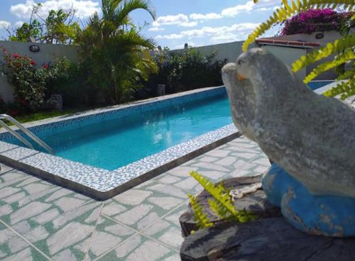 a statue of a bird sitting next to a swimming pool at Pousada Vale Encantado in Serra de São Bento