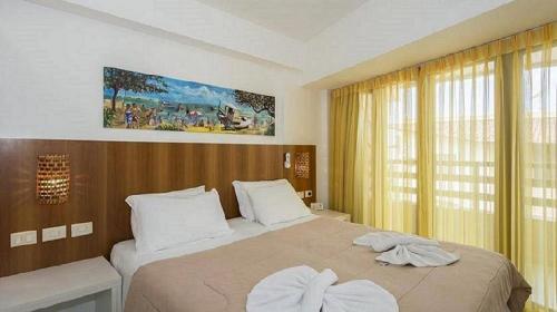 a bedroom with a large bed with two towels at Sonia Flats Pipa's Bay - Flat 121 in Pipa