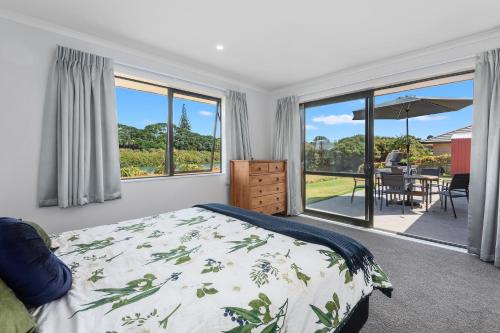 ルアカカにあるThe Waterfront Ruakaka - Ruakaka Holiday Homeのベッドとパティオの眺めのあるベッドルーム