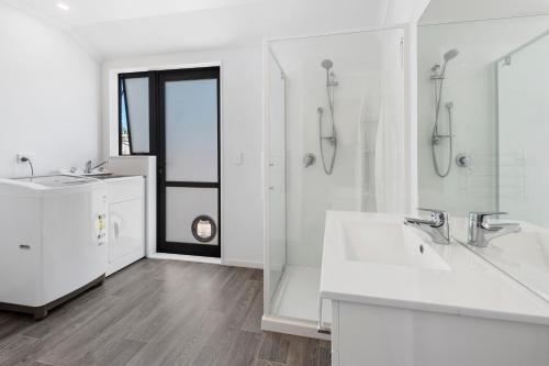 ルアカカにあるThe Waterfront Ruakaka - Ruakaka Holiday Homeの洗面台2つとシャワー付きの白いバスルーム