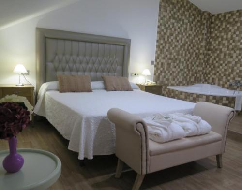 a bedroom with a large white bed and a chair at Hotel Restaurante Boabdil in Otura