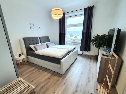 1 dormitorio con 1 cama, TV y ventana en Moderne Wohlfühloase zentral in Seenähe - Pillow menu, 2 Stk 55" Smart TVs, NETFLIX, DisneyPlus uvm, en Wetter