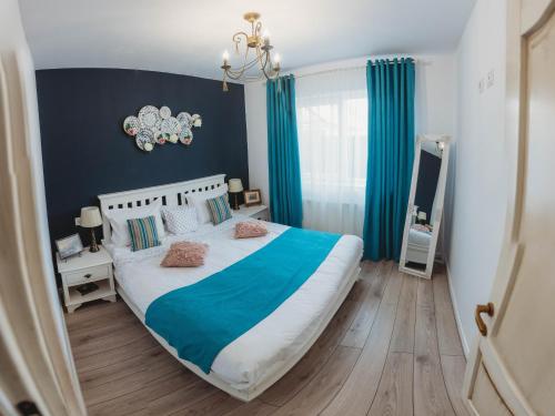 1 dormitorio con 1 cama grande y cortinas azules en La Contessa, en Tîrgu Neamţ
