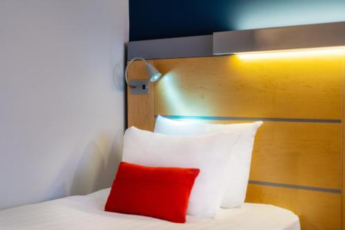 a bed with a red pillow and a wooden headboard at Holiday Inn Express Dundee by IHG in Dundee
