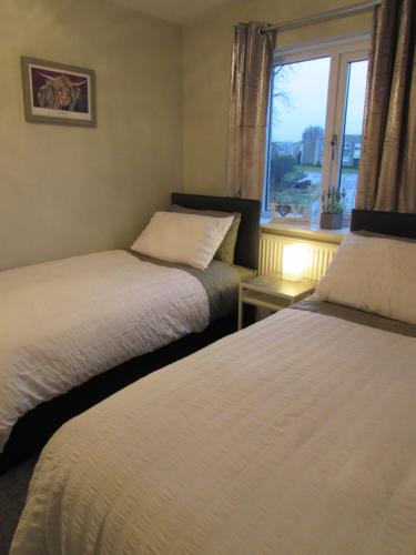 two beds in a room with a window at Levenview Holiday Apartment Loch Lom in Balloch