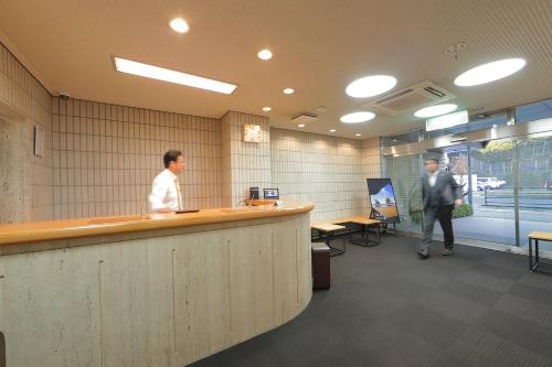 two men standing at a bar in a office at Hotel Sun Garden Matsuyama in Matsuyama