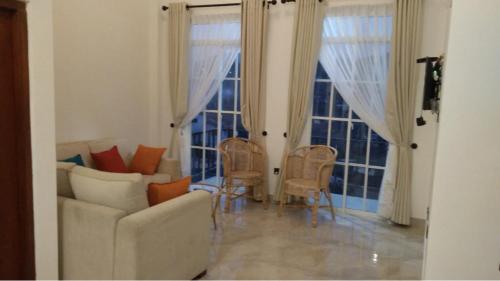 - un salon avec un canapé, des chaises et des fenêtres dans l'établissement Regal Rose Luxury Holiday Apartments, à Nuwara Eliya