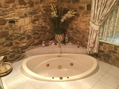 a bath tub with a vase with flowers in it at The OldDevonshire House in Mintaro